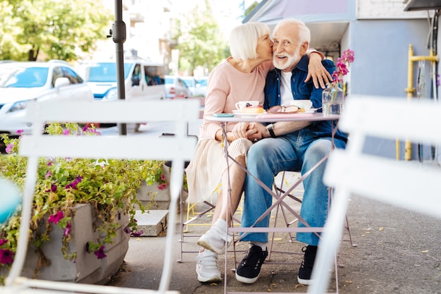 Foto freudiges älteres paar, das im café sitzt und küsst