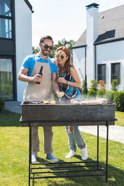 Freudiges Ehepaar, das beim Vorbereiten des Grillens zusammensteht