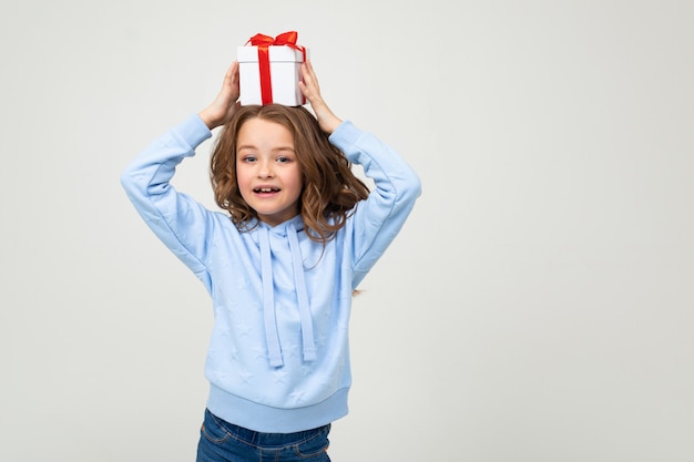 Freudiges glückliches kaukasisches Mädchen erhielt ein Geschenk an einer weißen Wand mit Leerzeichen