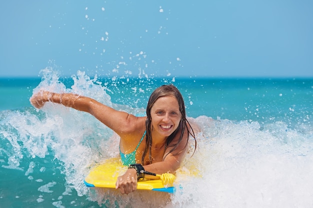 Foto freudiges junges mädchen auf bodyboard hat spaß auf meereswellen.