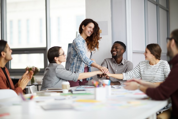 Freudiges Kreativteam, das sich im Meeting zusammenkauert