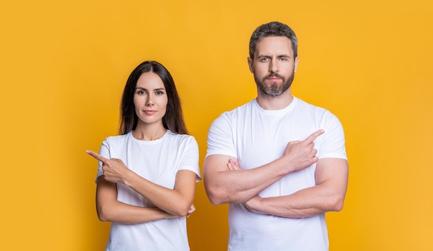 Freund und Freundin zeigen auf den Finger Paar von Mann und Frau isoliert auf gelb Familie Paar zeigt auf den Finger Millennial Mann und Frau machen Angebot Angebot von Millennial Paar Werbung