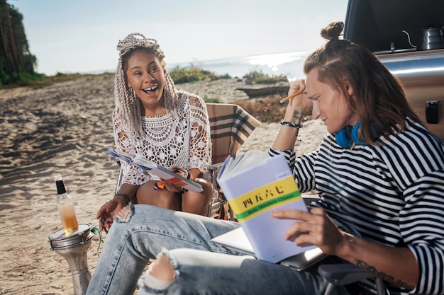 Freund unterrichten. Lustige Frau mit weißen Dreadlocks, die lachen, während sie ihrem Freund Chinesisch beibringen