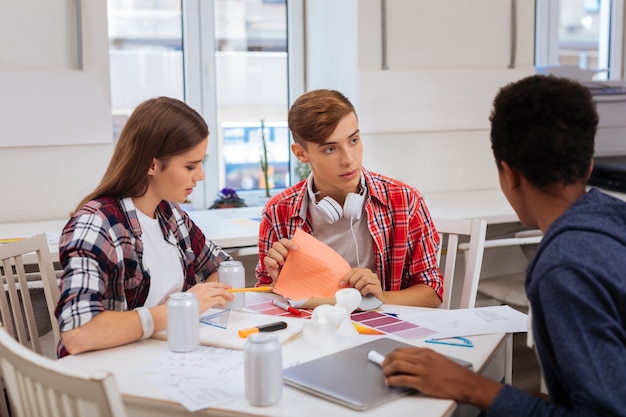 Freunde beitreten. Schöne blonde Studentin, die sich ihren Freunden in der Bibliothek anschließt, während sie zusammen studiert