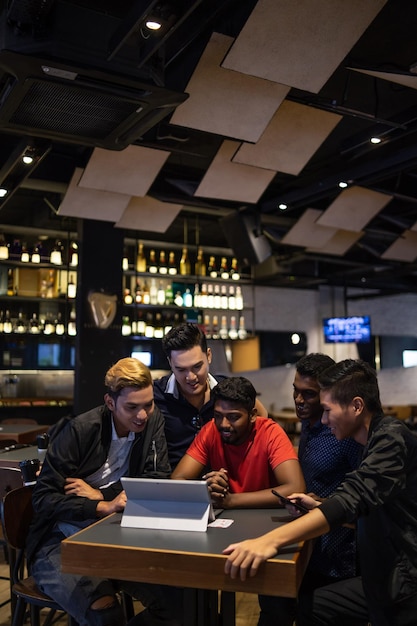 Freunde benutzen einen Laptop, während sie im Restaurant sitzen
