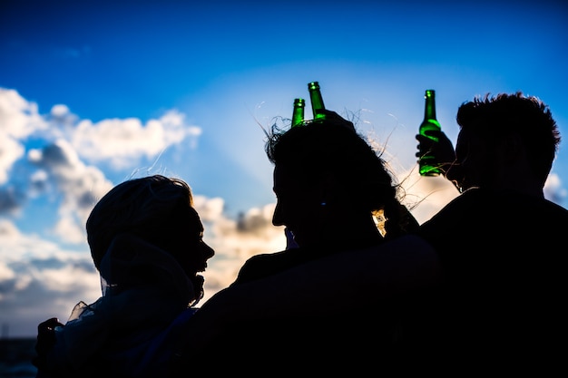 Freunde, die abgefülltes Bier am Strand trinken