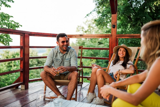 Freunde, die auf dem hölzernen Balkon in der Natur sich entspannen.