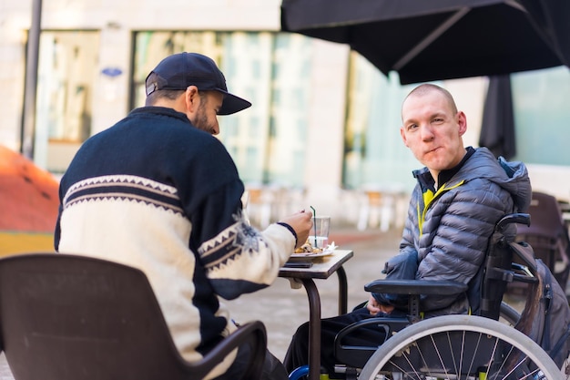 Freunde, die auf einer Restaurantterrasse essen Behinderte Rollstuhl