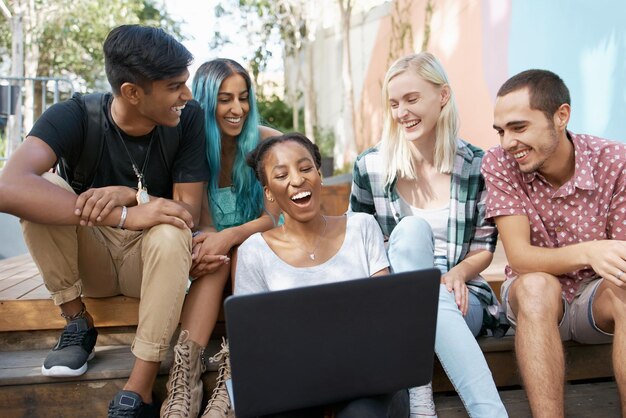 Foto freunde, die auf stufen sitzen und auf laptops schauen