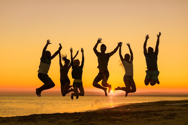 Freunde, die bei Sonnenuntergang am Strand am Meer springen