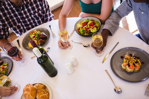 Freunde, die bei Tisch Lebensmittel und Wein im Restaurant genießen