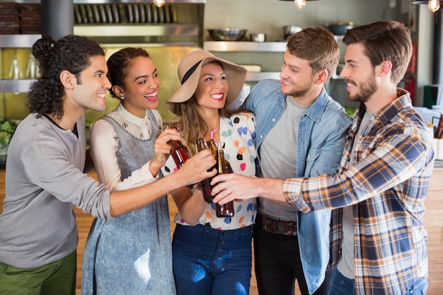 Foto freunde, die bierflaschen im restaurant rösten