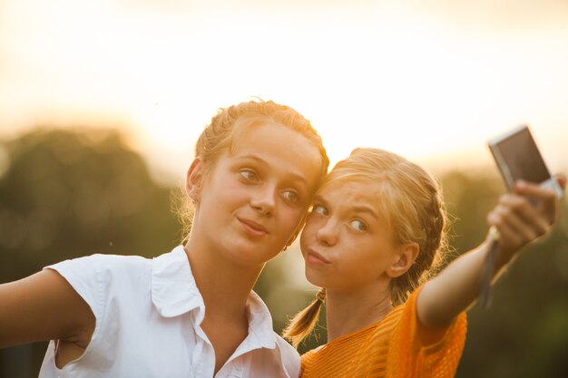 Freunde, die ein Selbstporträt im Freien machen. Zwei Mädchen machen Selfie im Sommerglühen