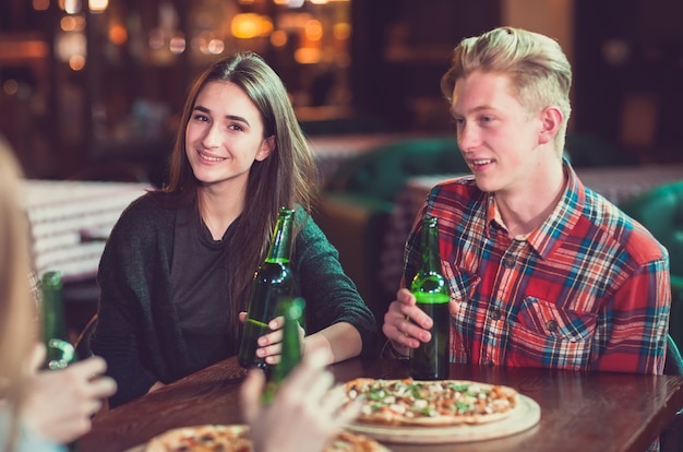 Freunde, die Getränke haben und Pizza in einer Bar essen