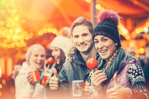 Foto freunde, die glühwein auf weihnachtsmarkt trinken