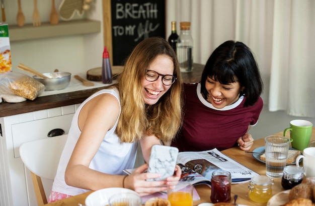 Freunde, die Handy beim Frühstücken betrachten