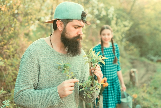 Freunde, die im Garten arbeiten, Mann, der Frühlingszweig im Garten arbeitet, Landwirtschaft und Menschen Konzept Transplantation