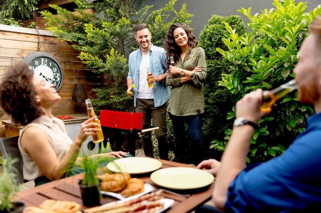 Foto freunde, die lebensmittel grillen und grillparty draußen genießen