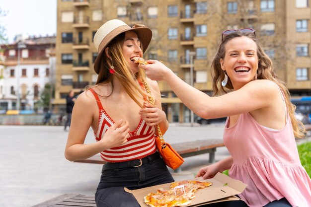 Freunde, die Pizza in der Stadt essen, genießen die Ferien beim Spielen und einer füttert den anderen Freund