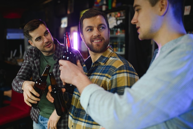 Freunde, die Spaß haben Fröhliche junge Männer in Freizeitkleidung trinken Bier im Pub