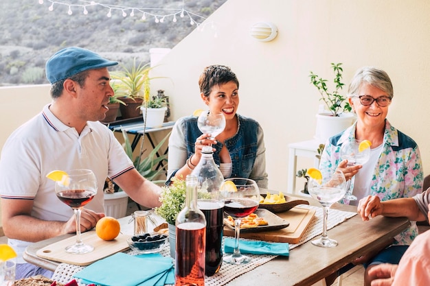 Freunde, die Spaß haben und gemeinsam Mittagessen mit Speisen und Getränken auf dem Tisch genießen Kaukasische Menschen gemischten Alters feiern und genießen Freundschaft zu Hause im Freien Traditionelles Familienveranstaltungskonzept