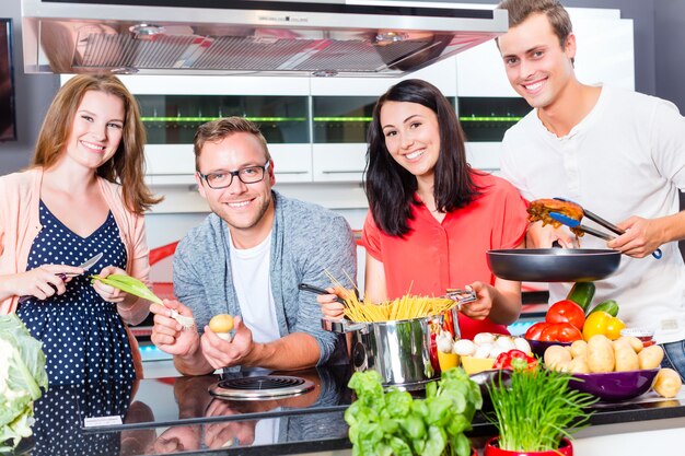 Freunde, die Teigwaren und Fleisch in der inländischen Küche kochen