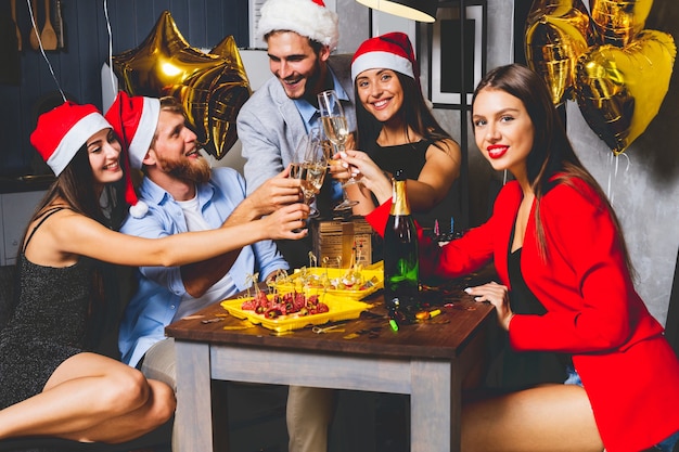 Freunde, die Weihnachten oder Silvester feiern. Partytisch mit Champagner