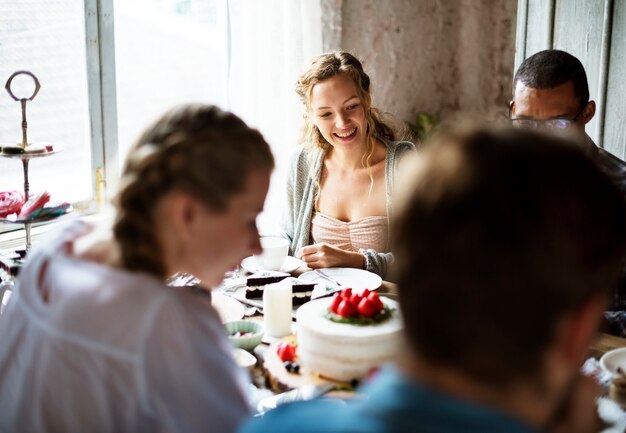 Freunde, die zusammen auf Teeparty essen Kuchen-Genussglück sammeln