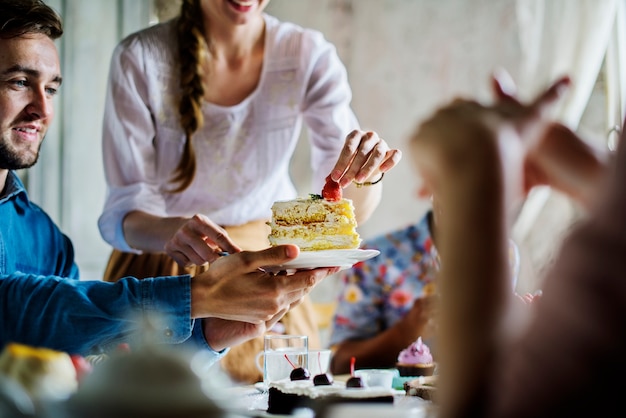 Freunde, die zusammen auf Teeparty essen Kuchen-Genussglück sammeln