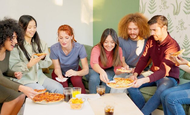 Freunde, die zusammen zu Hause Pizza essen und lächeln