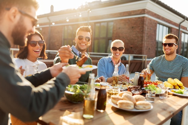 Freunde essen Abendessen oder BBQ-Party auf dem Dach