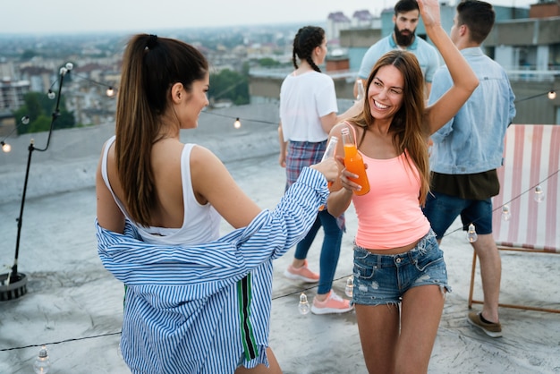 Freunde genießen Cocktails auf einer Party. Gruppe glücklicher Menschen, die Spaß haben und auf einem Dach tanzen?