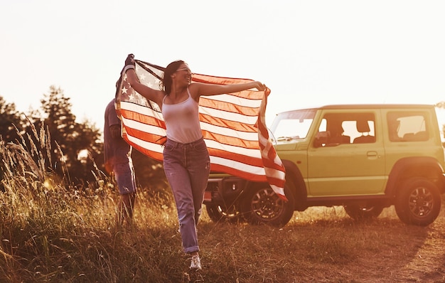 Foto freunde haben ein schönes wochenende im freien in der nähe ihres grünen autos mit der usa-flagge