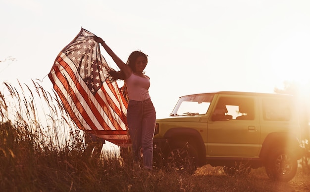 Freunde haben ein schönes Wochenende im Freien in der Nähe ihres grünen Autos mit der USA-Flagge