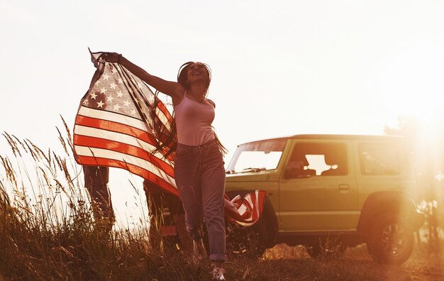 Freunde haben ein schönes Wochenende im Freien in der Nähe ihres grünen Autos mit der USA-Flagge