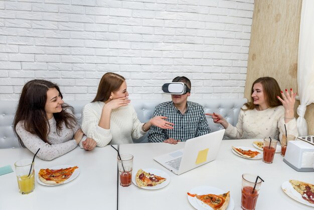 Freunde im Café essen Pizza und probieren eine virtuelle 3D-Brille aus