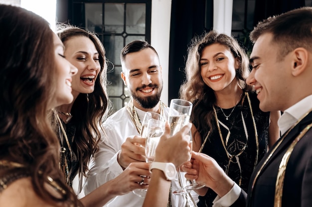 Freunde in stilvoller, eleganter Kleidung lächeln zusammen und halten Gläser Champagner in den Händen