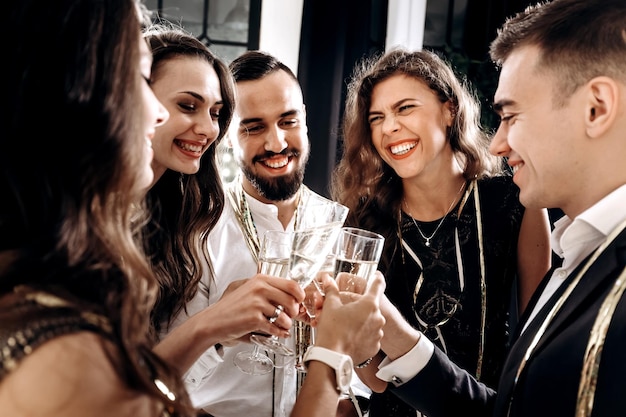 Freunde in stilvoller, eleganter Kleidung lächeln zusammen und halten Gläser Champagner in den Händen