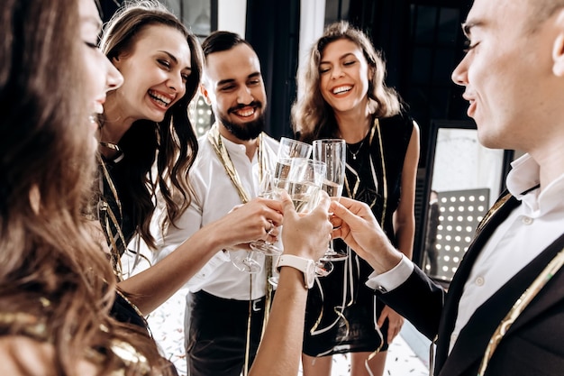 Freunde in stilvoller, eleganter Kleidung lächeln zusammen und halten Gläser Champagner in den Händen