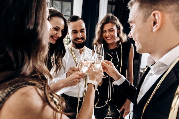 Freunde in stilvoller, eleganter Kleidung lächeln zusammen und halten Gläser Champagner in den Händen