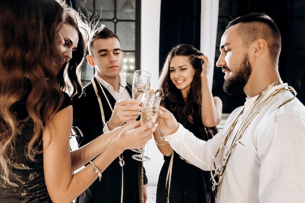 Freunde in stilvoller, eleganter Kleidung lächeln zusammen und halten Gläser Champagner in den Händen