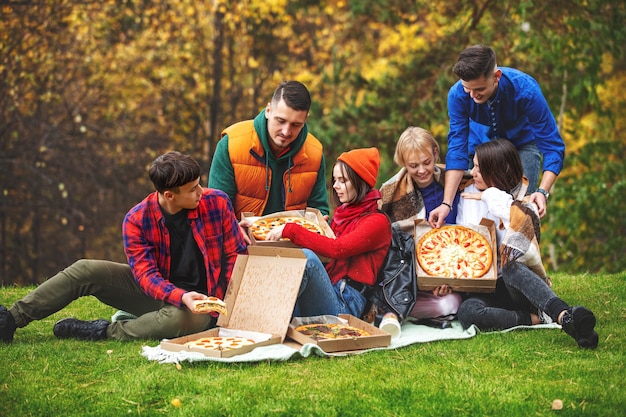 Freunde junge lustige schöne genießen Pizza und Geselligkeit auf einem Picknick in der Natur zusammen