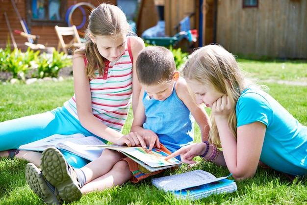 Freunde Kinder lesen Buch Outdoori auf Gras