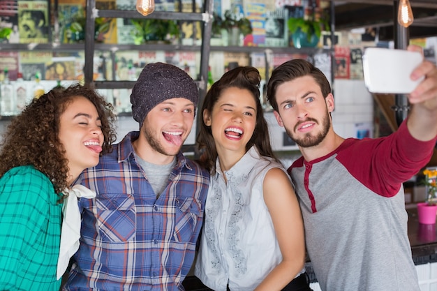 Freunde machen Gesichter, während sie Selfie im Restaurant sprechen