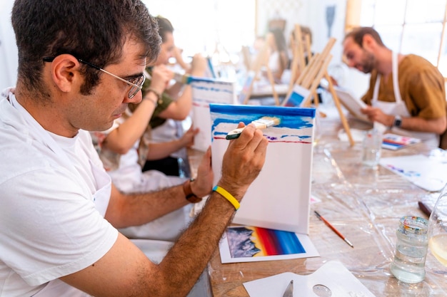 Freunde malen in einer Kunst- und Weinwerkstatt. Mann mittleren Alters malt