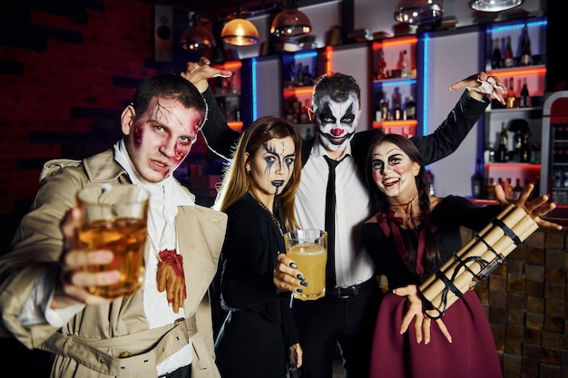 Freunde mit Bombe in den Händen sind auf der thematischen Halloween-Party in gruseligem Make-up und Kostümen.