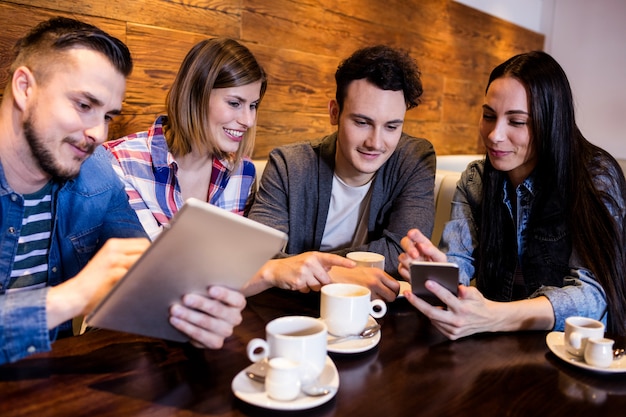 Freunde mit digitalem Tablet und Handy im Restaurant