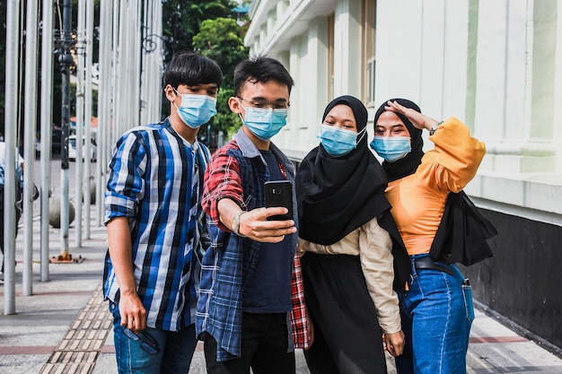 Freunde mit schützender Sicherheitsmaske haben Spaß daran, Selfies während der Koronavirus-Pandemie zu machen