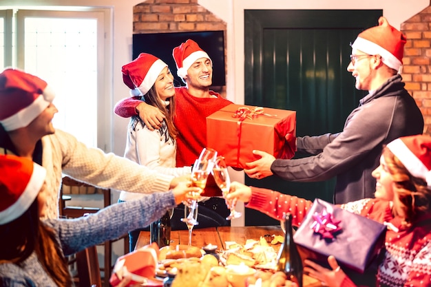 Freunde mit Weihnachtsmütze geben sich gegenseitig Weihnachtsgeschenk