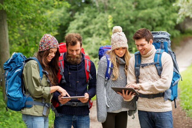 Foto freunde oder reisende mit rucksäcken und tablet-pc